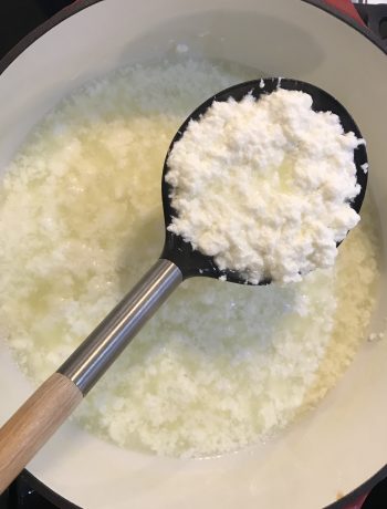 ricotta in a slotted spoon held over the cooking pot