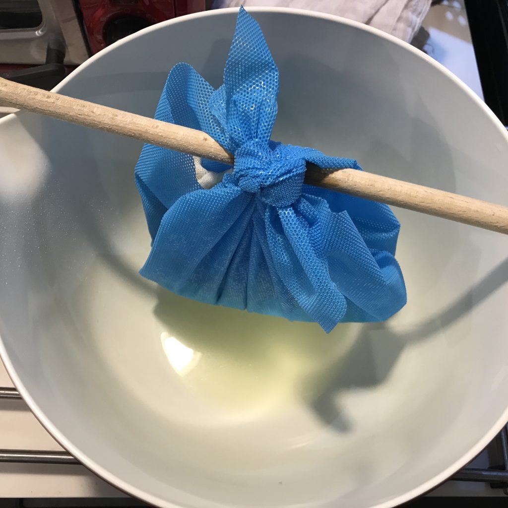 Goat's milk cheese inside of 2 layers of cheesecloth, hung over a bowl to drain.